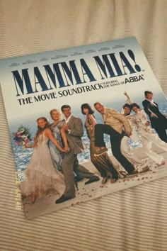 the movie poster for mamma mia is laying on top of a bed with sheets