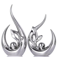 two silver metal sculptures with leaves and balls on the top, one is shaped like a bird