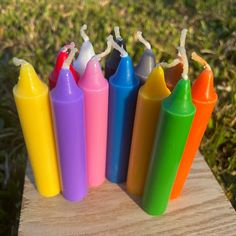 several different colored crayons sitting on top of a wooden table in the grass