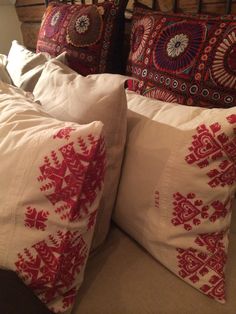 two pillows on a bed with red and white designs