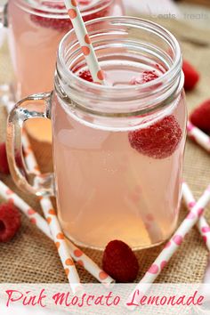 two mason jars filled with raspberry lemonade and topped with fresh strawberries