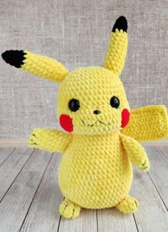 a crocheted pikachu stuffed animal sitting on top of a wooden floor