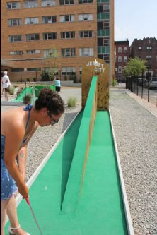 a woman is playing mini golf in the city