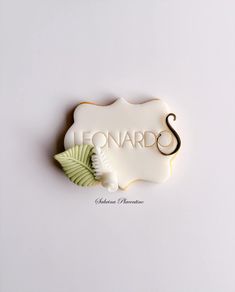 a cookie with the word lemonade written in white icing and decorated with green leaves