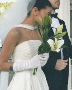 a man and woman in wedding attire standing next to each other with flowers on their hands