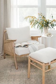 a white chair and ottoman in front of a window with flowers on the windowsill