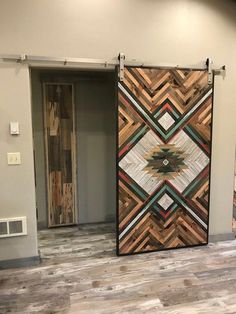 a large wooden door in the middle of a room with wood flooring and white walls