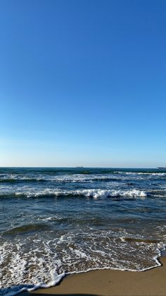 the ocean waves are rolling in and out of the water on a sunny day at the beach