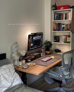 a desk with a computer on it in front of a book shelf filled with books