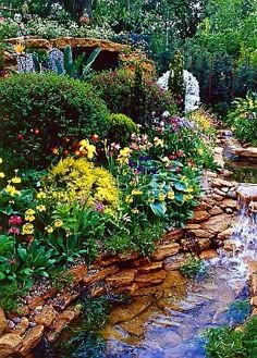 a garden filled with lots of different types of flowers and plants next to a stream