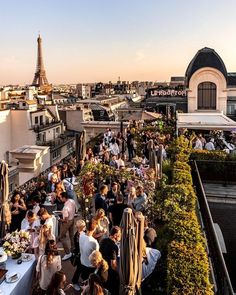 people are sitting at tables on the roof of a building with an eiffel tower in the background