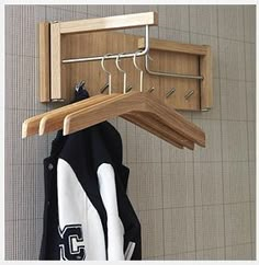 a coat rack with two coats hanging from it's hooks and clothes hangers