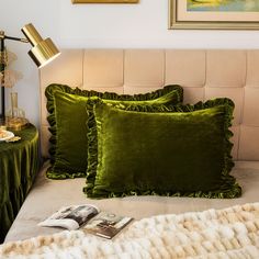 a bed with two green pillows on top of it and a magazine next to it