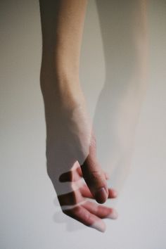 a person's hand reaching for something in the air with their shadow on the wall