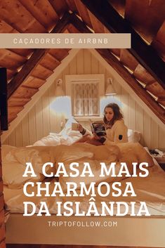 a woman sitting on top of a bed in a loft next to a window with the words acasa mais charmosa da islanda