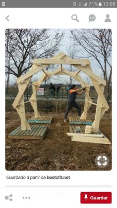 a man standing in front of a wooden gazebo on top of a dirt field