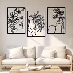 three black and white paintings on the wall above a couch