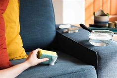 a person holding a sponge on top of a couch next to a bowl of food