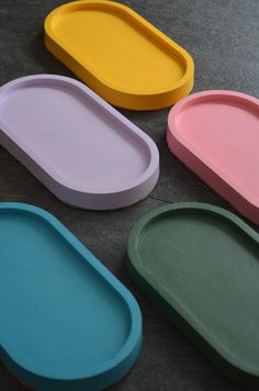 four different colored trays sitting on top of a black table next to each other