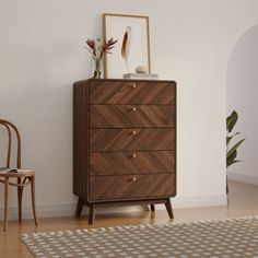 a wooden dresser sitting next to a chair on top of a hard wood floor in front of a white wall