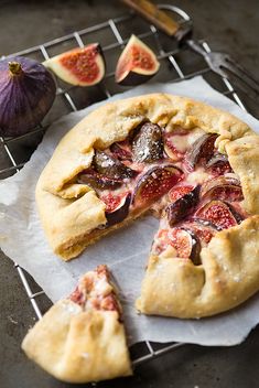 a pizza with one slice missing from it on a cooling rack next to figs