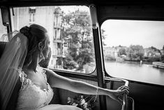 a woman in a wedding dress sitting on a bus looking out the window at water