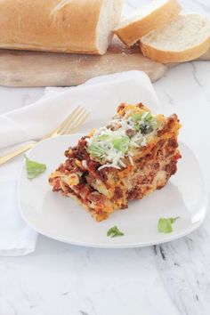 a white plate topped with lasagna and bread