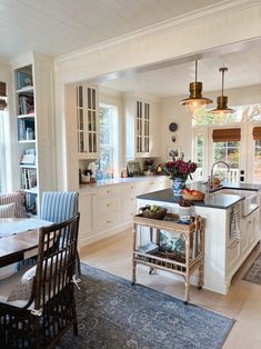 a kitchen filled with lots of white cabinets and counter top next to a dining room table