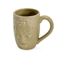 a ceramic mug with a face on it's side and an embossed design in the middle