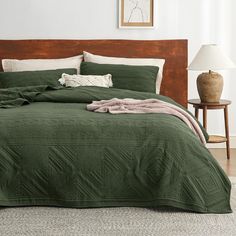 a bed with green bedspread and pillows