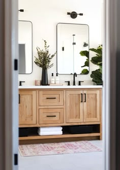 a bathroom with two mirrors and wooden cabinets