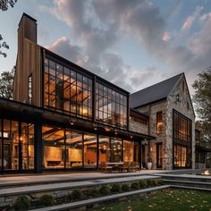 a large house with lots of windows on the front and side of it at dusk