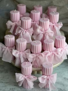 there are many pink candles that have bows on them in the shape of bowes