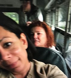 two women are sitting on a bus and one is looking at the camera