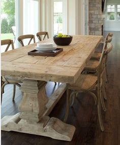 a wooden table with chairs around it and a bowl of fruit on the dining room table