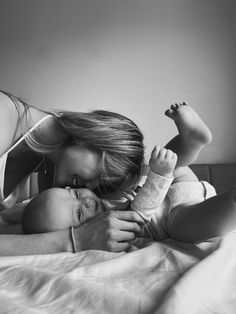 a woman laying on top of a bed holding a baby