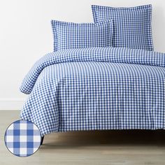 a blue and white checkered comforter set with two pillows on the bottom bed