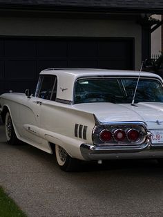 an old white car parked in front of a garage