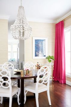 a dining room table with white chairs and a chandelier hanging from the ceiling