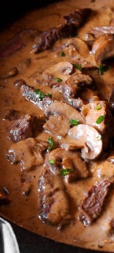 a pot filled with meat and mushrooms covered in gravy on top of a table