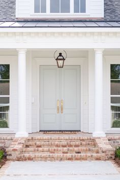 a white front door with two windows and brick steps