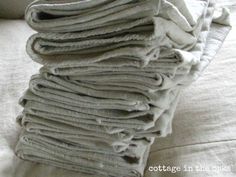 a stack of folded linens sitting on top of a white bed sheet covered in wrinkle