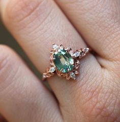 a close up of a person's hand with a green ring on their finger