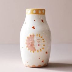 a white vase with gold and pink designs on the front, sitting on a table