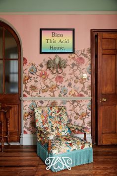 a chair sitting in front of a pink wall with flowers on it and a sign that says bliss this acid house