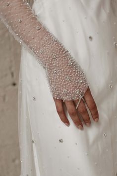 a close up of a person's hand wearing a wedding dress