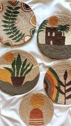 four woven coasters with designs on them sitting on a white cloth covered bed sheet