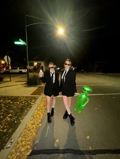 two women dressed in black and white posing for the camera on a street at night