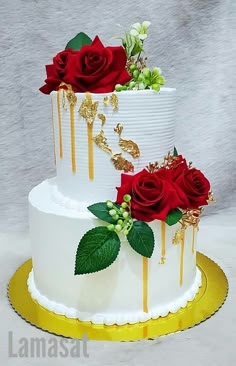 two tiered wedding cake decorated with red roses and gold drips on white frosting