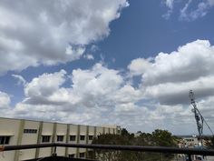 the sky is filled with white clouds and there are cars parked in front of it